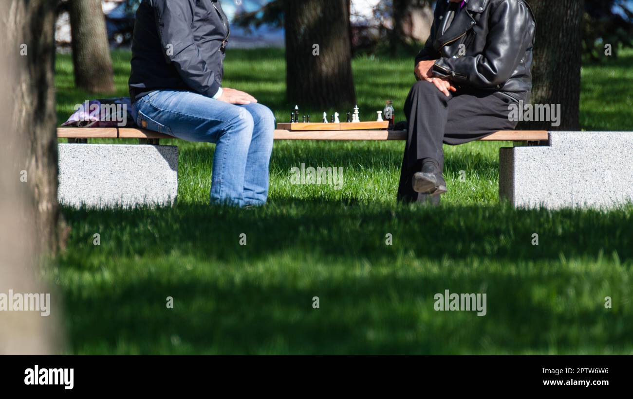 Deux hommes jouant au jeu d'échecs sur un banc dans un parc public vert aire de loisirs Banque D'Images
