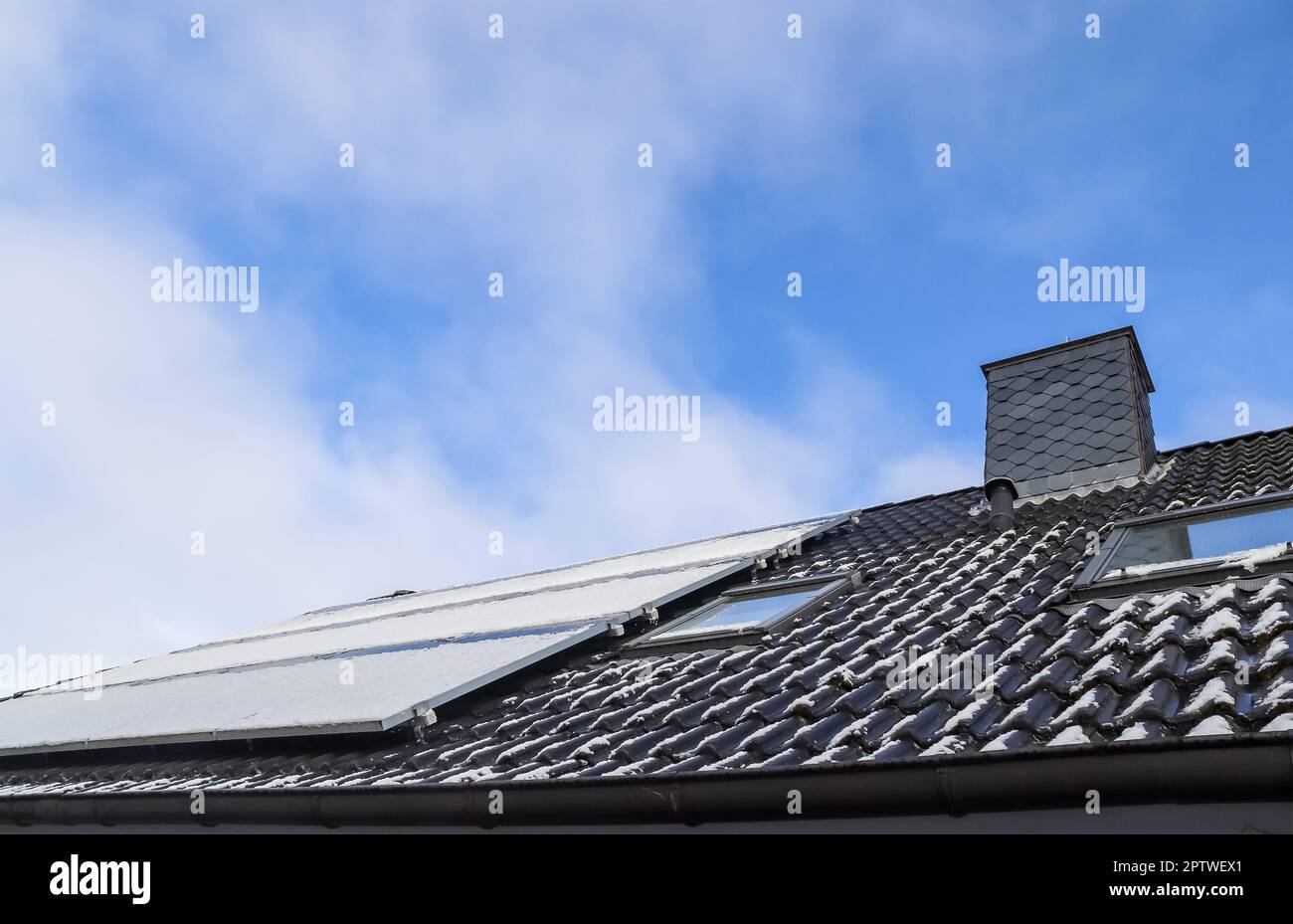 Panneaux solaires avec de la neige sur elle produisant de l'énergie propre sur un toit d'une maison résidentielle Banque D'Images