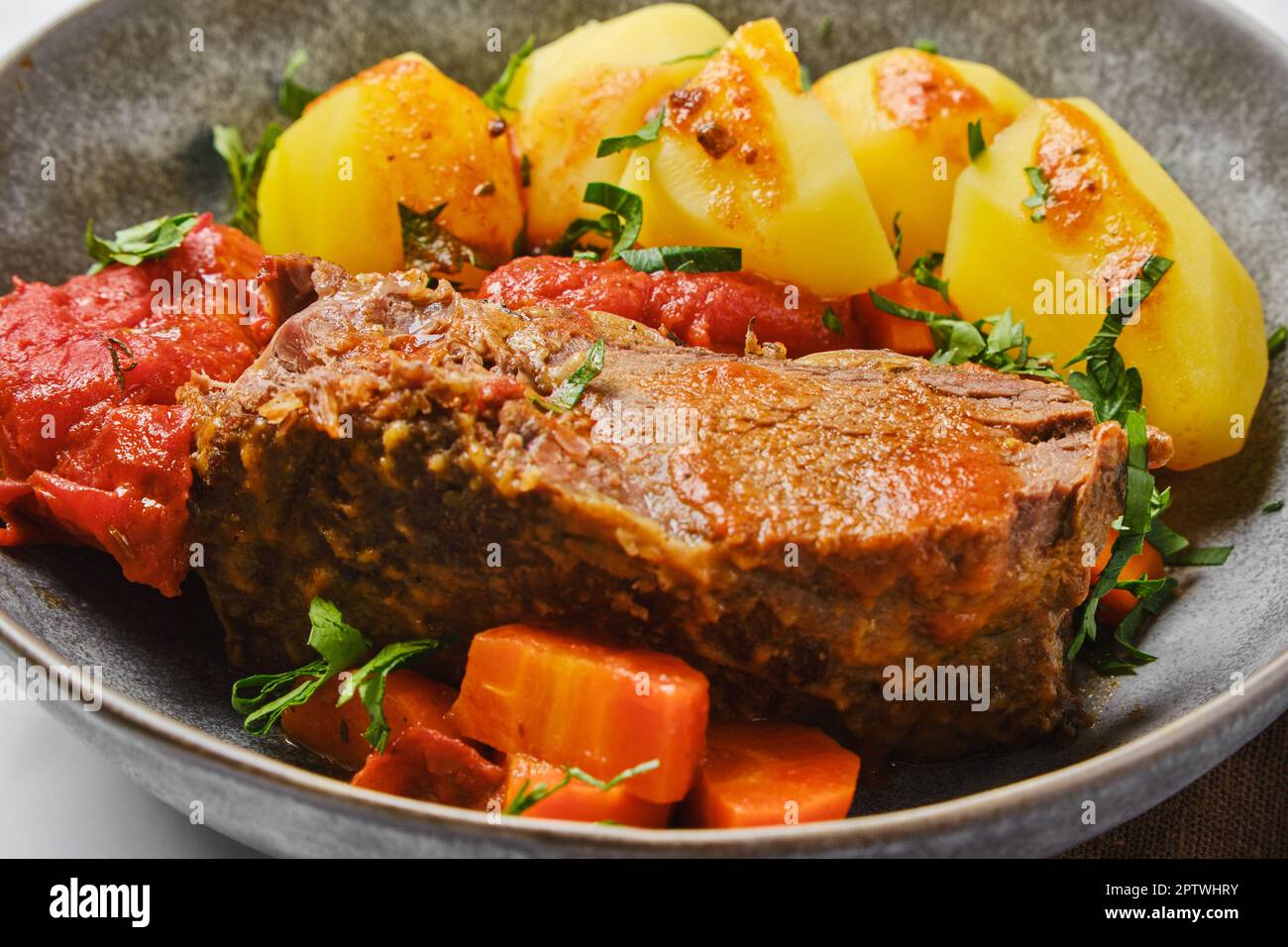 Vue en gros plan de la viande de rôti de bœuf rond cuite dans de la sauce à la bière avec des tomates et des carottes Banque D'Images
