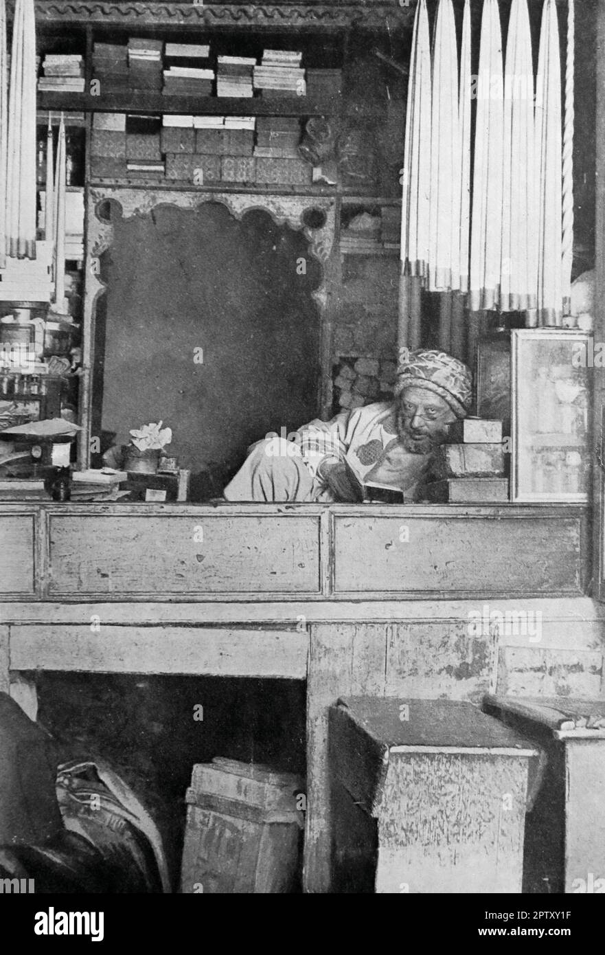 La vie au Maroc, Afrique, c1905. Un commerçant tunisien. Un homme a claché, lisant un livre, dans sa boutique. De la photo d'Albert photo, Tunis. Banque D'Images