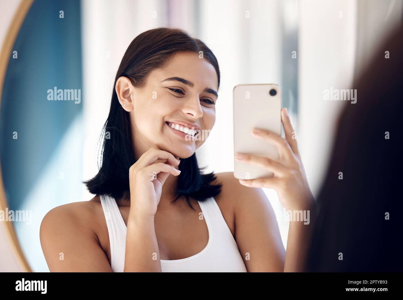 Miroir selfie, femme heureuse et téléphone, beauté et soins de la peau dans  la salle de bains de la maison. Sourire jeune fille prenant la photo dans  la réflexion, mobile et social