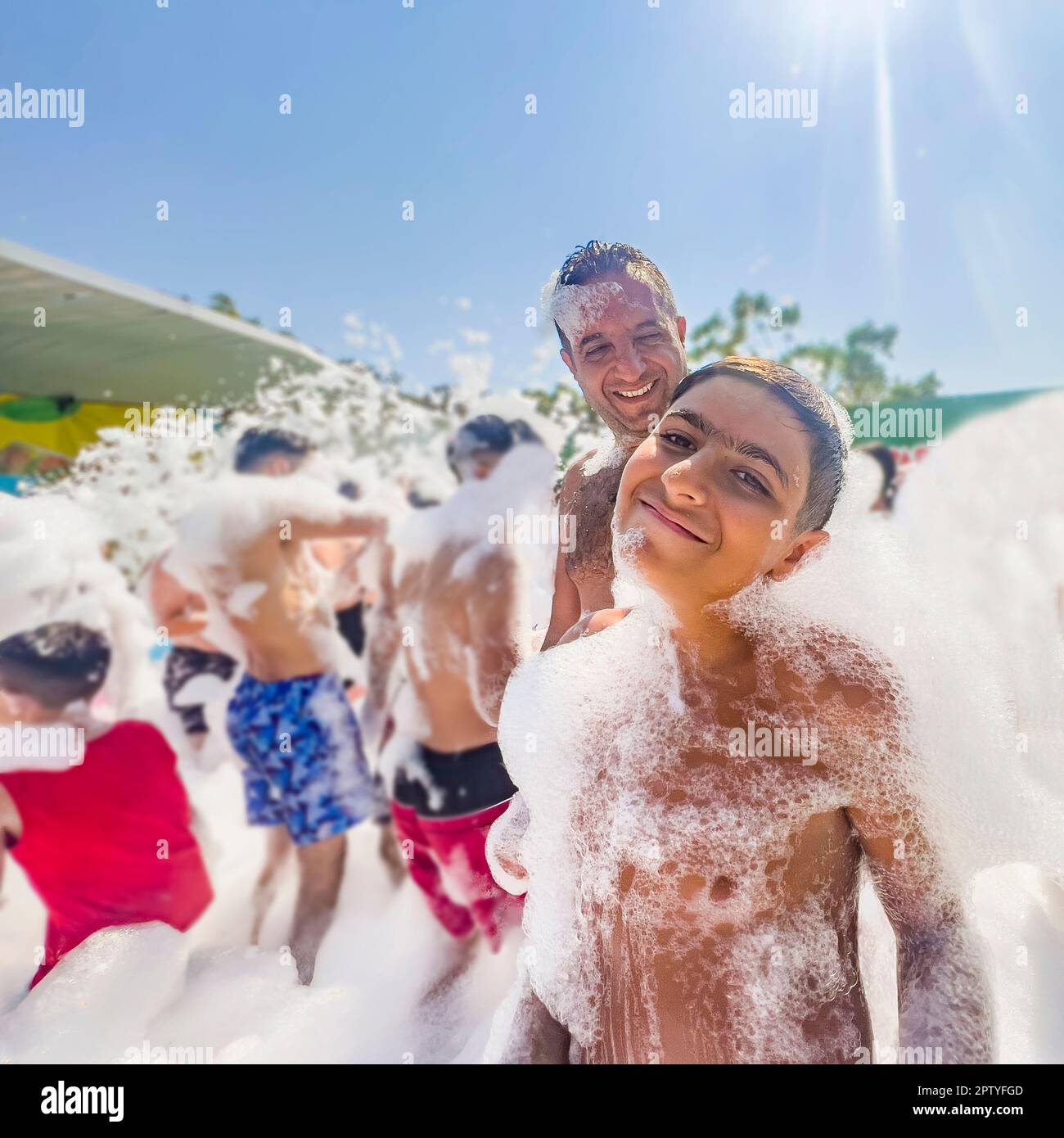 Père et fils qui s'amusent une journée au parc aquatique. Concept d'été: Flou personnes méconnaissables jouant à la fête de la piscine de mousse. Les enfants dansent sur la piste de danse Banque D'Images Père et fils qui s'amusent une journée au parc aquatique. Concept d'été: Flou personnes méconnaissables jouant à la fête de la piscine de mousse. Les enfants dansent sur la piste de danse Banque D'Images