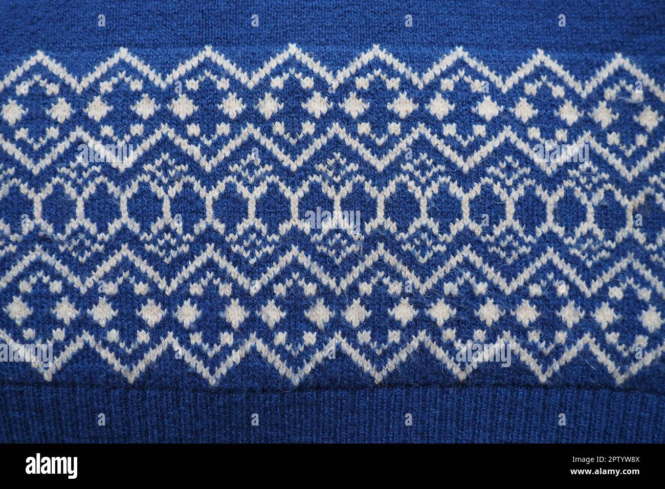 Motif jacquard tricoté. Tricoté en losange blanc et zigzag sur fond bleu. Décoration géométrique pour Noël ou nouvel an. Hiver t Banque D'Images