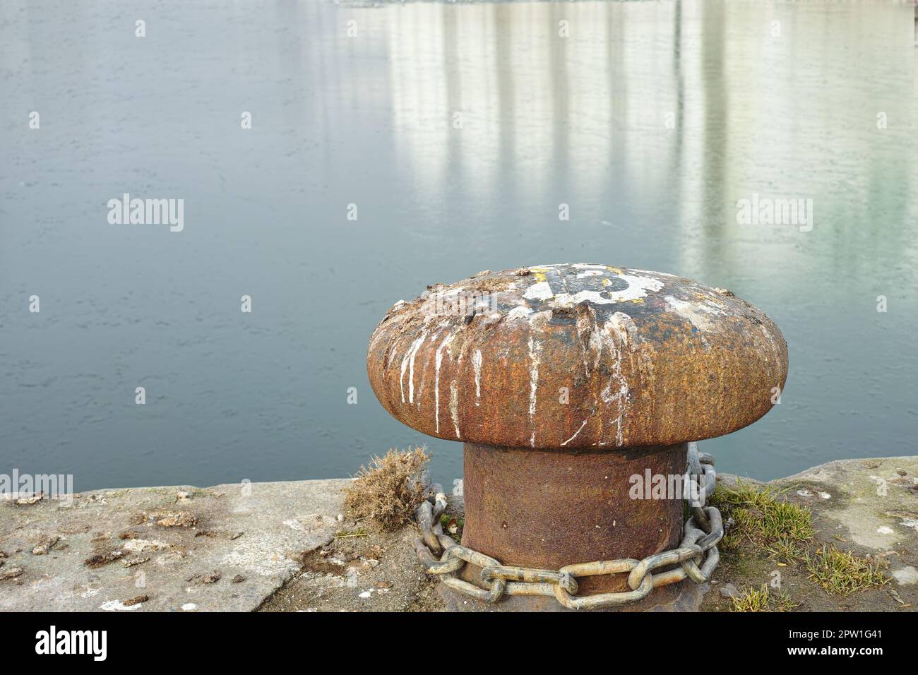 Un port de bollard à côté d'un port. Mouillage rouillé en fonte de bollard sur la rive de la jetée. Espace de copie d'arrière-plan ciel et eau. Point d'ancrage de fixation pour empêcher le vesse Banque D'Images