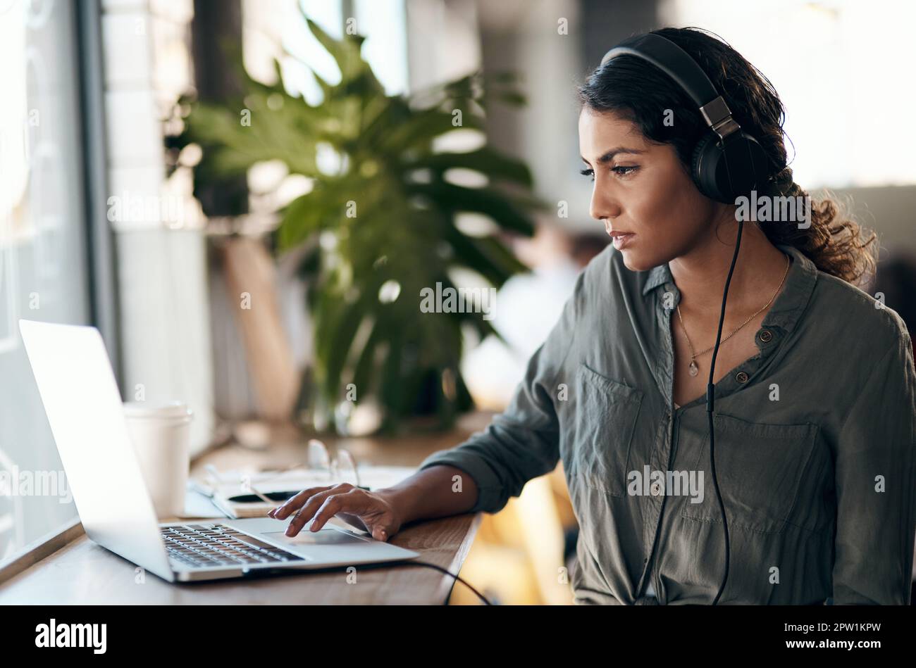 Une étudiante travaillant sur un ordinateur portable avec un casque pour un projet universitaire dans un café, un restaurant ou un café. Penser et étudier la jeune université Banque D'Images