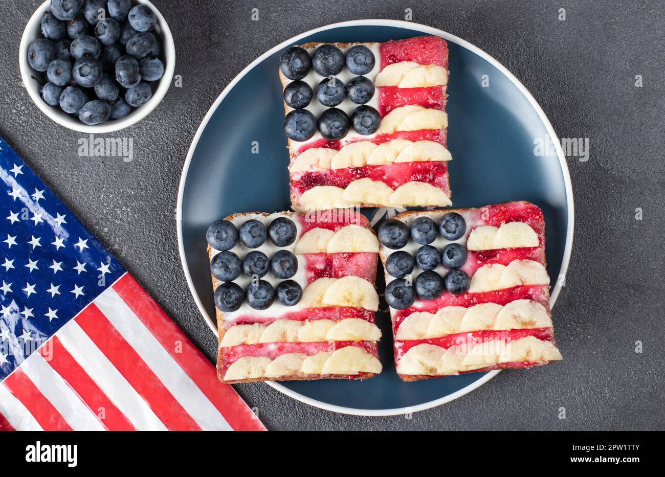 Sandwichs drapeau américain avec confiture de bleuets, de bananes et de baies sur pain grillé sur plaque bleue, vue du dessus Banque D'Images