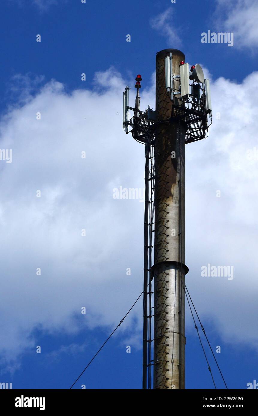 Cheminée en métal élevé d'installations industrielles avec échelle sous la forme d'accolades métalliques contre l'arrière-plan d'un ciel nuageux ciel bleu Banque D'Images