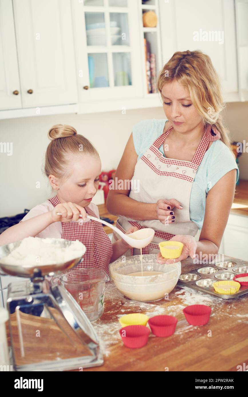 Préparer sa cuisson pour le four. Une petite fille mignonne qui cuit dans la cuisine à la maison avec sa mère Banque D'Images