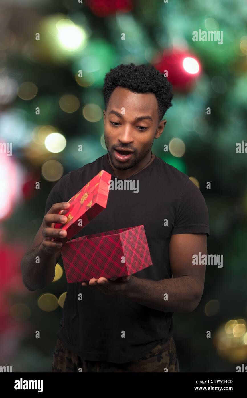 jeune homme recevant un cadeau et une boîte d'ouverture nuit de noël  surprise vacances surprise décorations bokeh lumière Photo Stock - Alamy