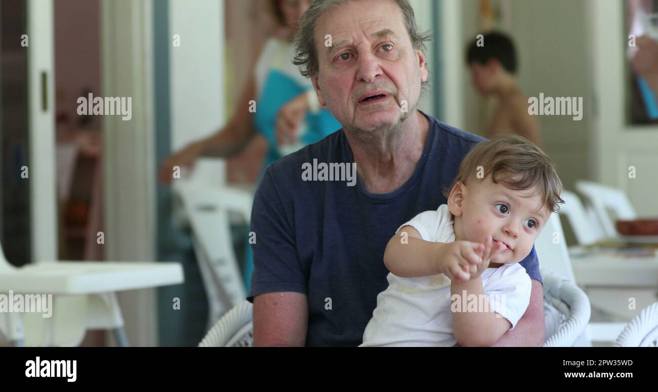 Bébé se claque les mains sur les genoux du grand-père Banque D'Images