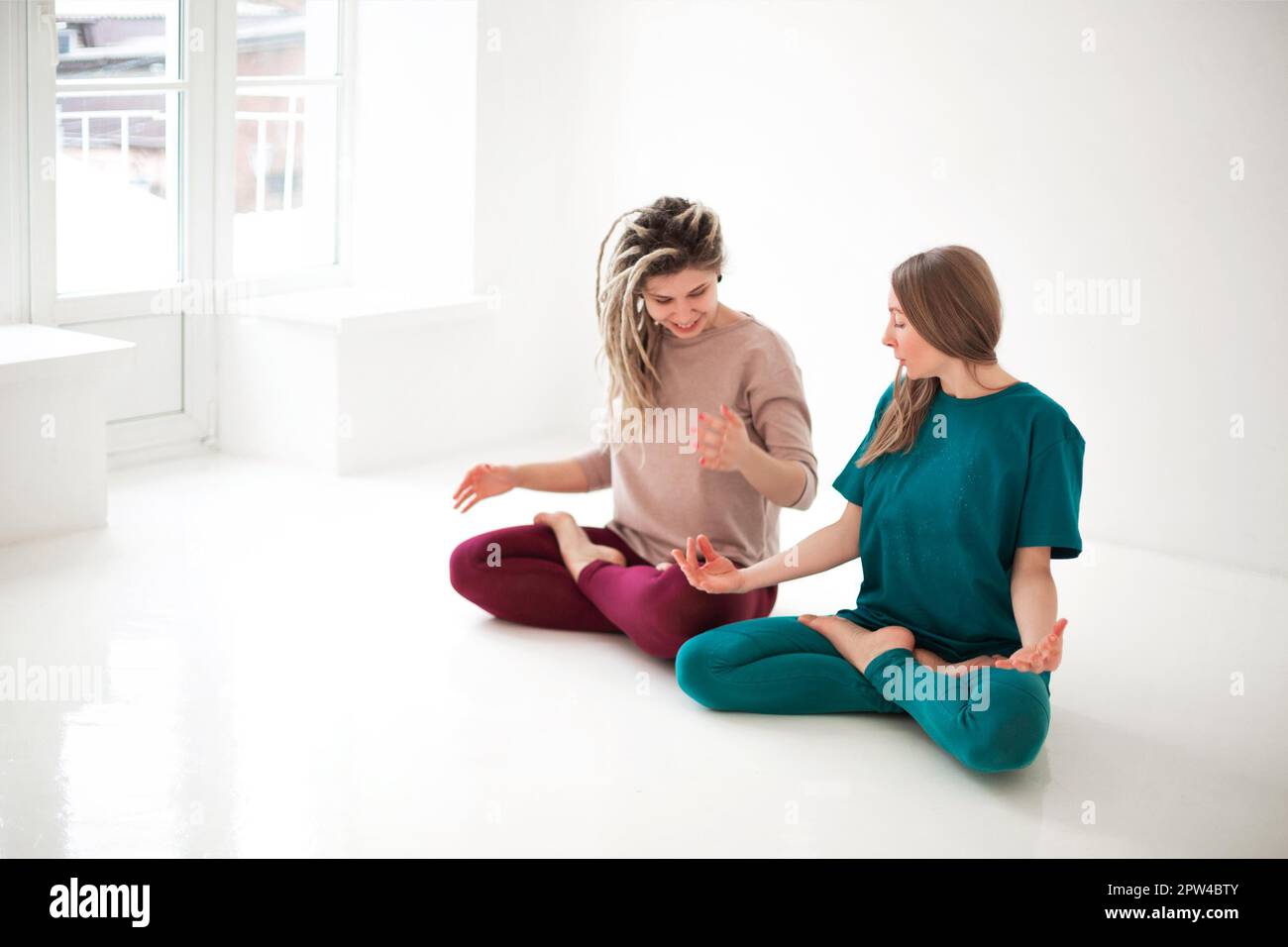Femme adulte aidant la femme dans les vêtements de sport avec faire la pose de yoga et bras d'étirement Banque D'Images
