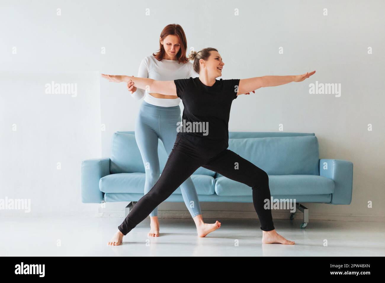 Femme adulte aidant la femme dans les vêtements de sport avec faire la pose de yoga et bras d'étirement Banque D'Images