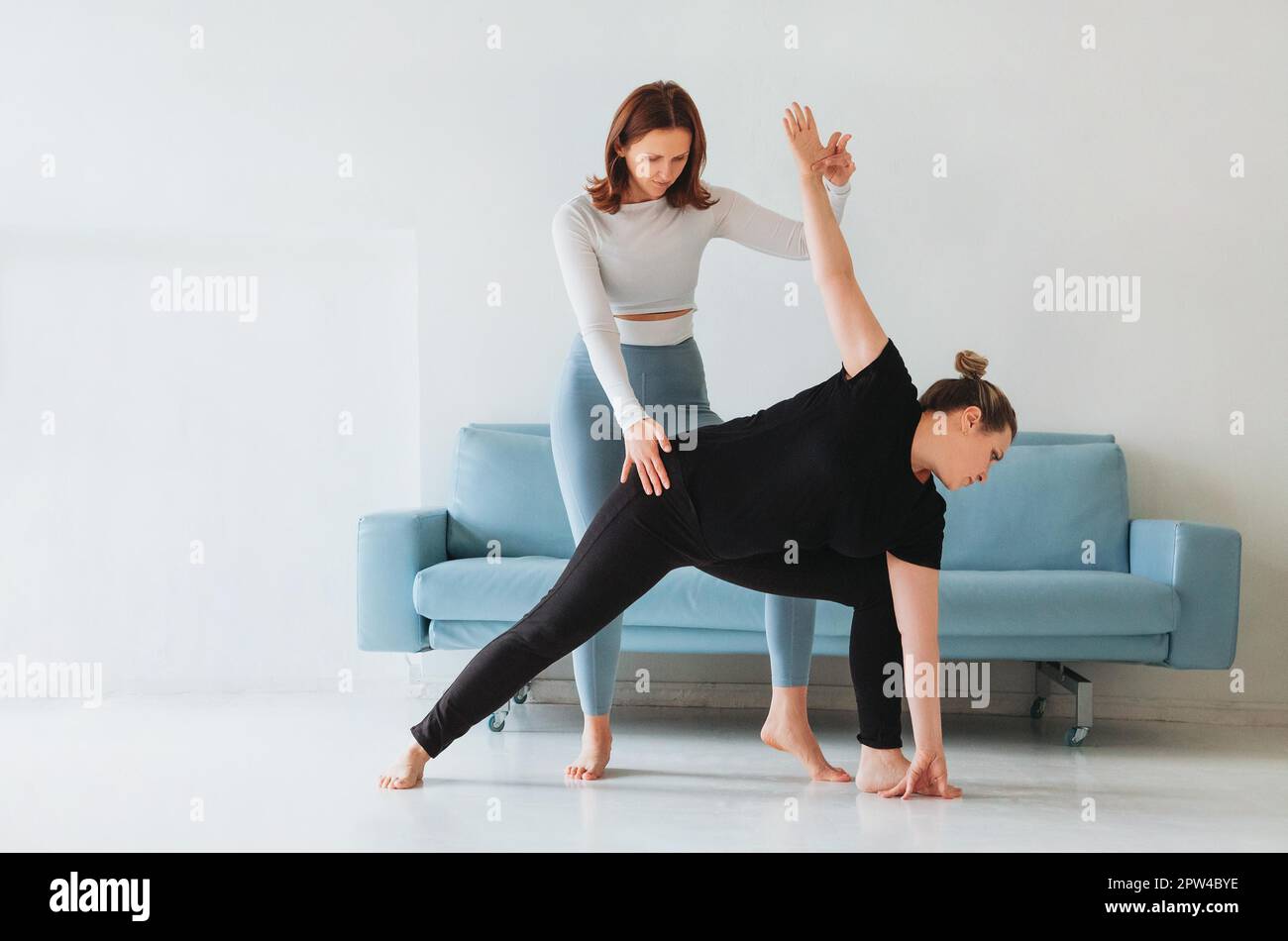 Femme adulte aidant la femme dans les vêtements de sport avec faire la pose de yoga et bras d'étirement Banque D'Images