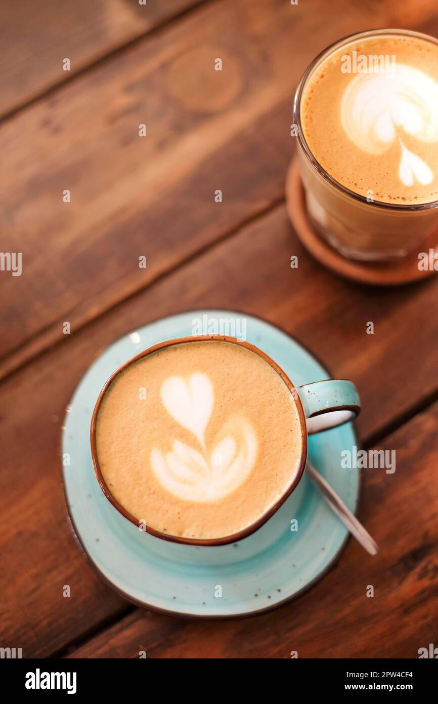 Du dessus des tasses en céramique sur les soucoupes fraîchement brassées latte avec les cœurs sur la mousse Banque D'Images