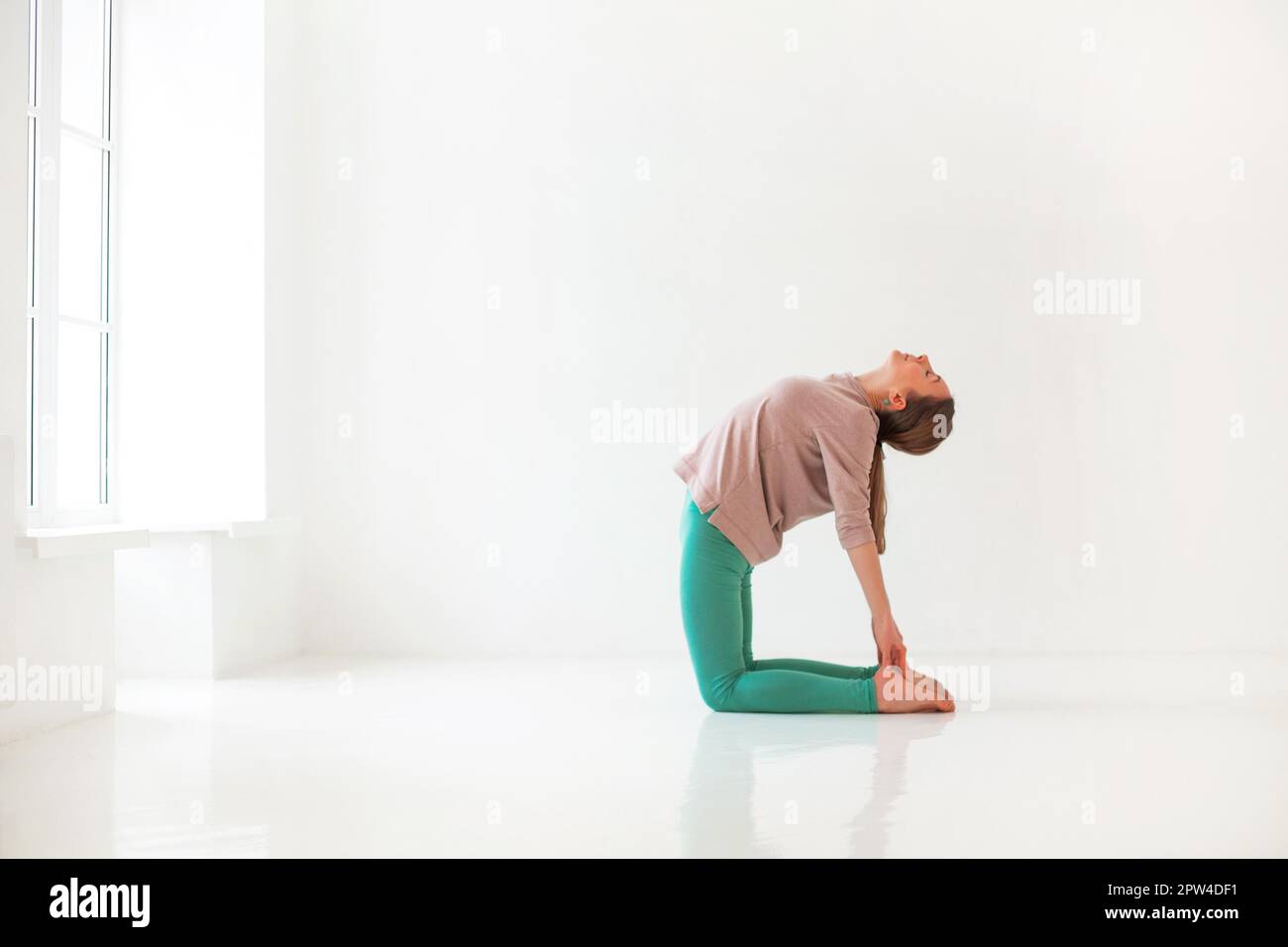 Calme femme dans les vêtements de sport pratiquant le yoga dans la posture de Firefly tout en équilibrant et en regardant loin Banque D'Images