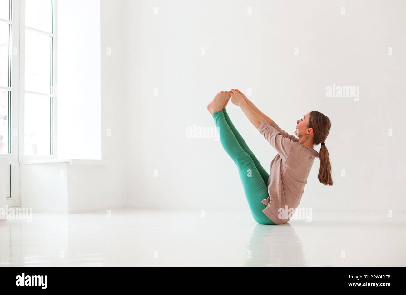 Calme femme dans les vêtements de sport pratiquant le yoga en posture tout en équilibrant et en regardant loin Banque D'Images