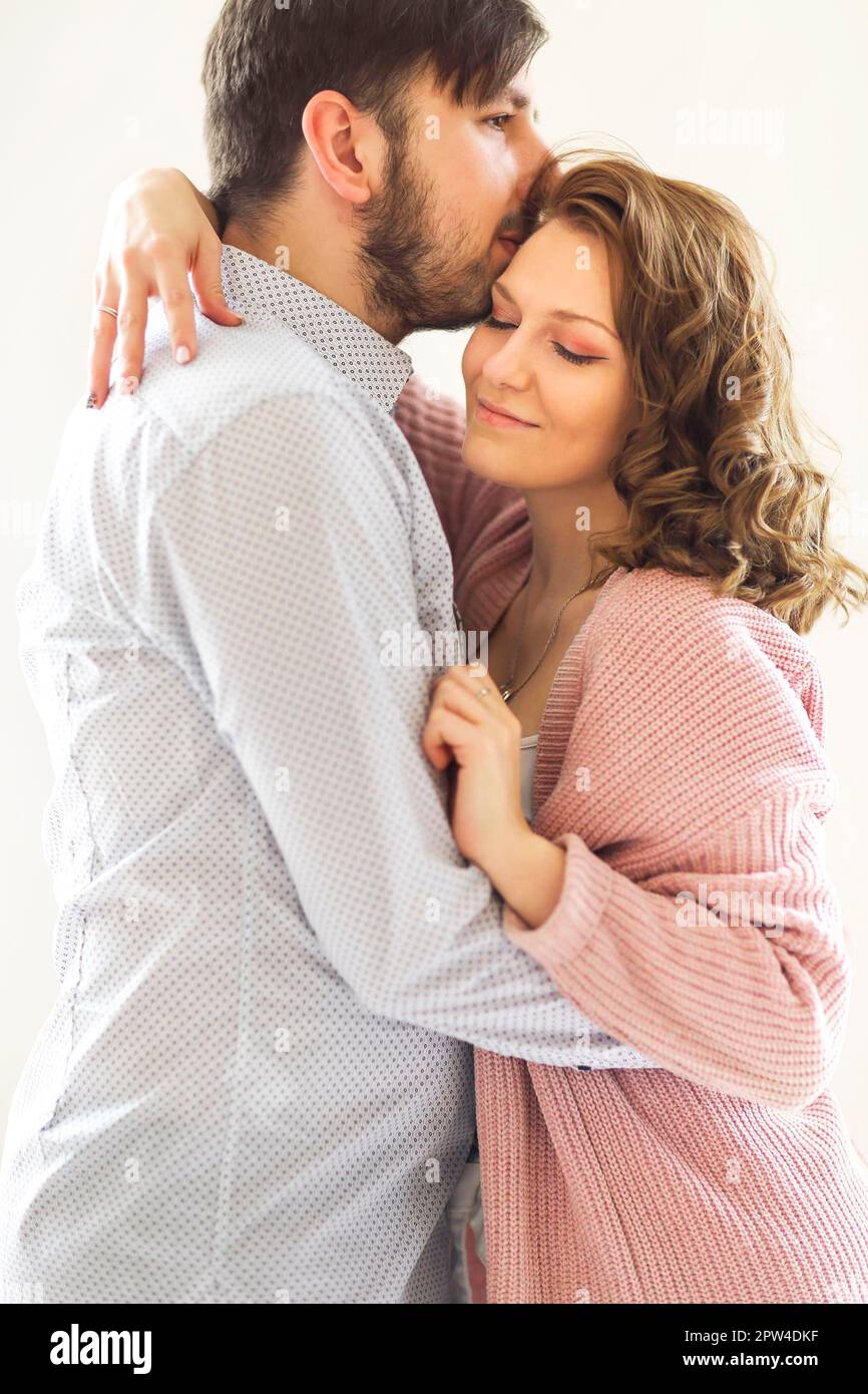 Vue latérale du couple amoureux du contenu qui s'embrasse doucement sur le blanc arrière-plan à la maison Banque D'Images