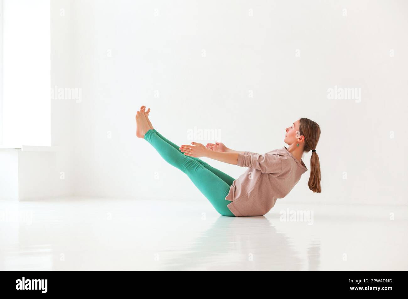 Calme femme dans les vêtements de sport pratiquant le yoga dans la posture de Firefly tout en équilibrant et en regardant loin Banque D'Images