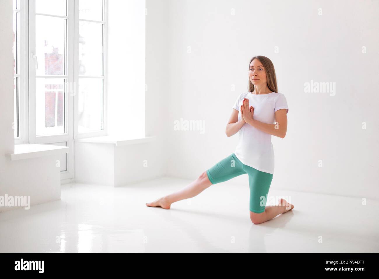 Calme femme dans les vêtements de sport pratiquant le yoga en posture tout en équilibrant et en regardant loin Banque D'Images