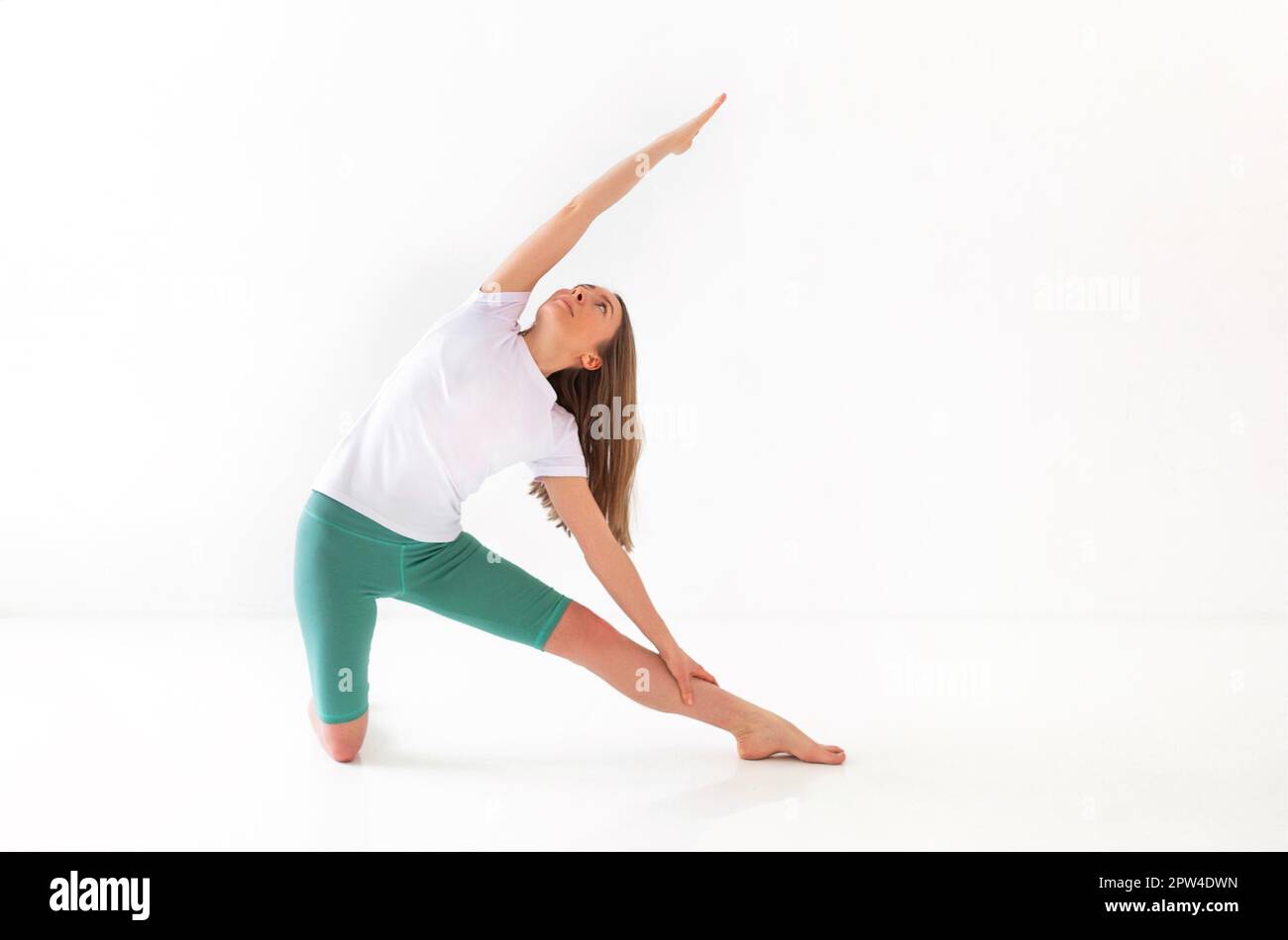 Calme femme dans les vêtements de sport pratiquant le yoga en posture tout en équilibrant et en regardant loin Banque D'Images