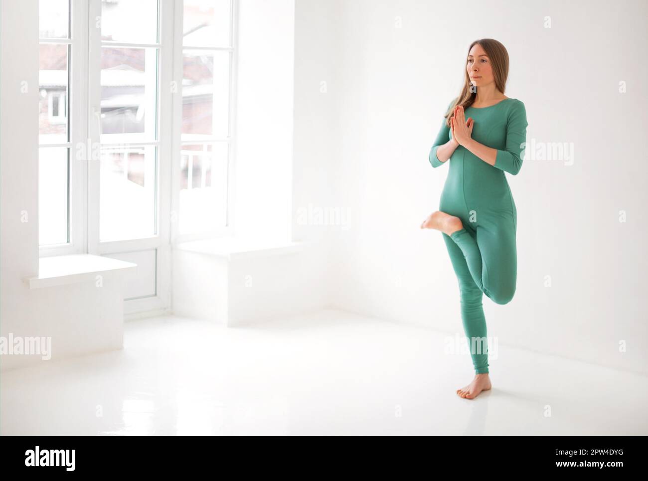 Calme femme dans les vêtements de sport pratiquant le yoga en posture tout en équilibrant et en regardant loin Banque D'Images