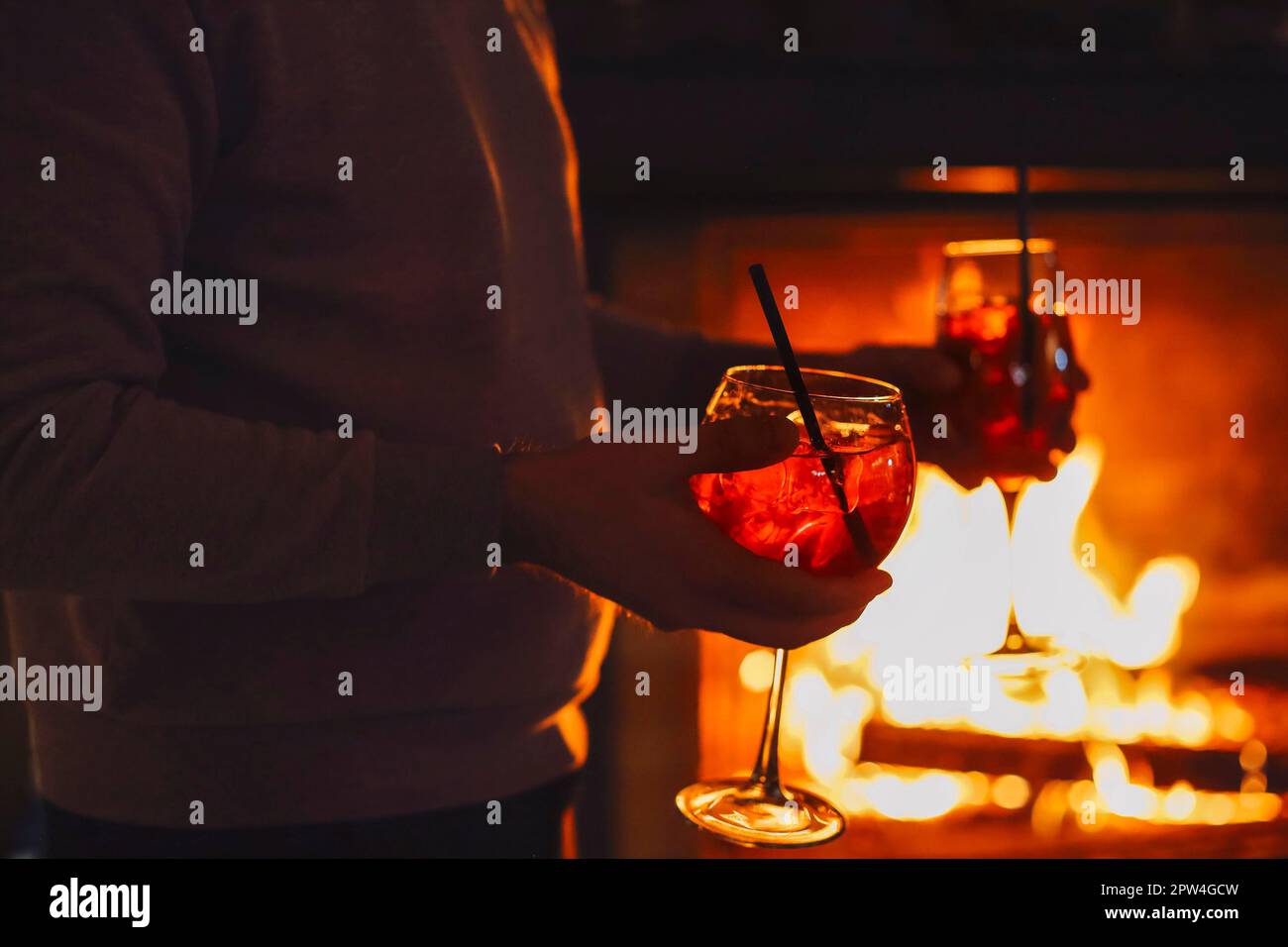 Croquez un homme méconnaissable dans une chemise décontractée tenant une paire de verres avec un cocktail d'alcool Apperol Spritz et des tranches d'orange lors d'une fête romantique Banque D'Images