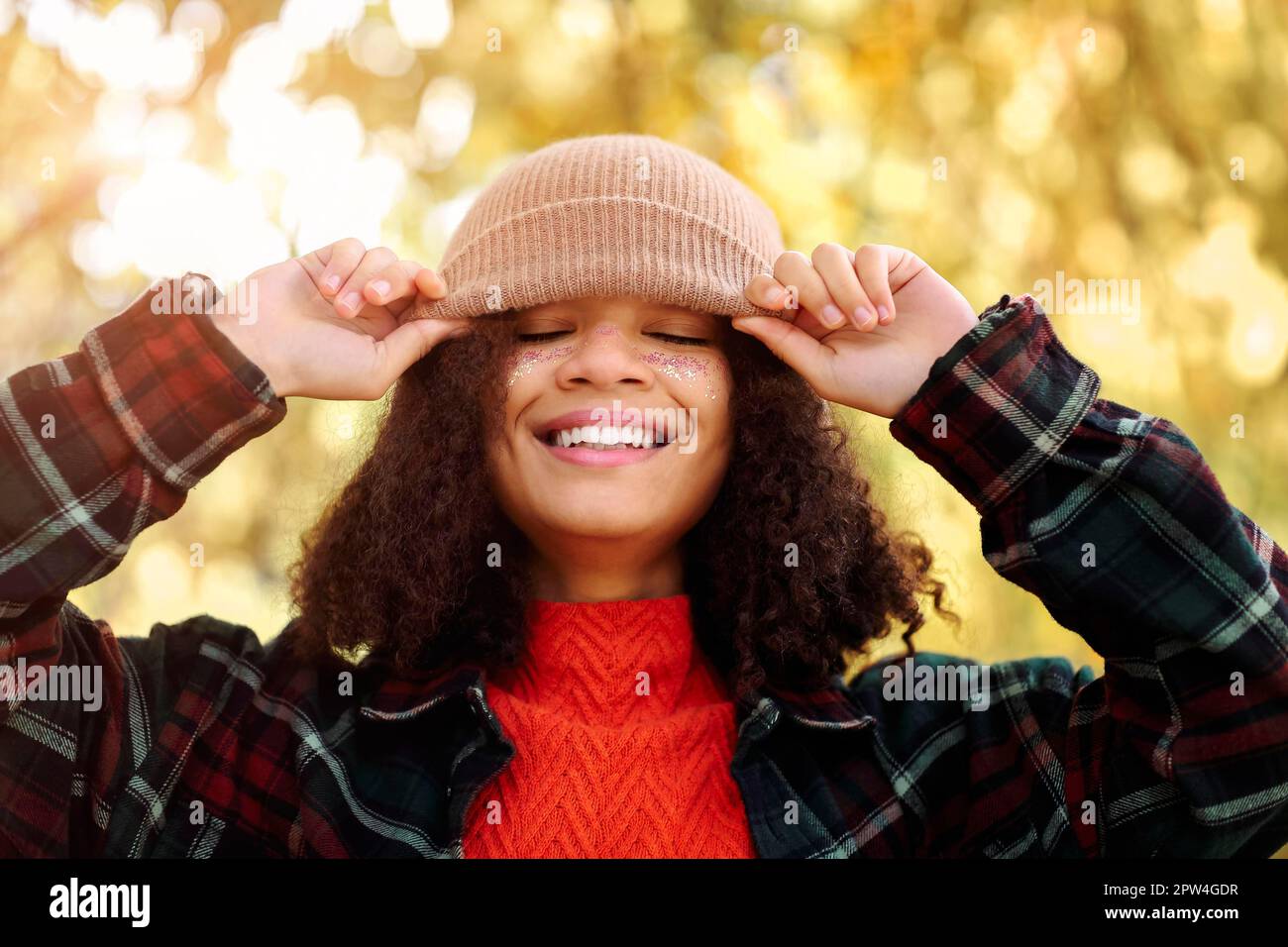 Jeune heureuse femme afro-américaine surjoyeuse avec des cheveux bouclés  ajustement bonnet beige tricoté et rire en se tenant dans la forêt  d'automne, insouciante Photo Stock - Alamy