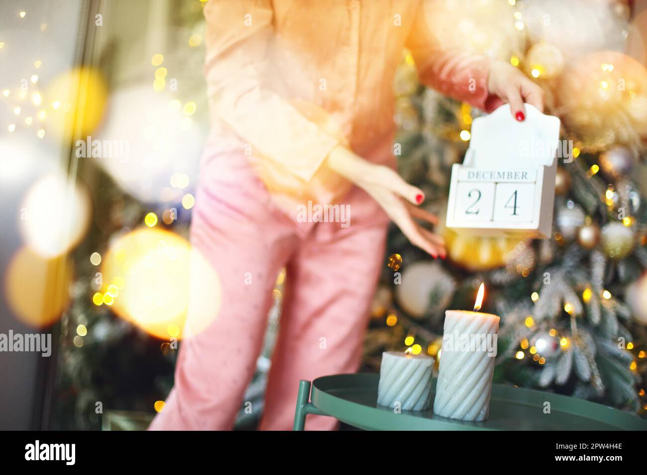 Jour de Noël. Coupe courte de femme dans un calendrier en bois pajama, du 24 au 25 décembre du matin, debout près d'un firmier décoré à la maison Banque D'Images