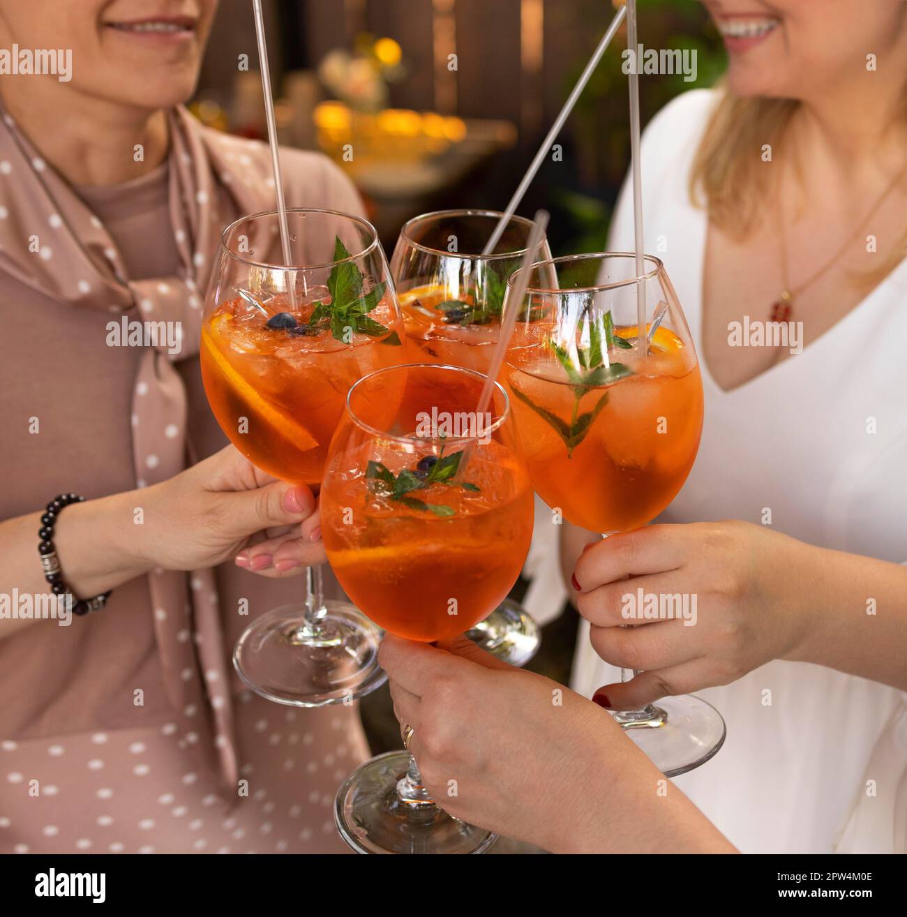 Des amis heureux passant du temps ensemble, se concentrer sur les jeunes femmes qui boivent le cocktail Aperol spritz. Fête de mariage d'été. Concept de bonheur et de célébration Banque D'Images