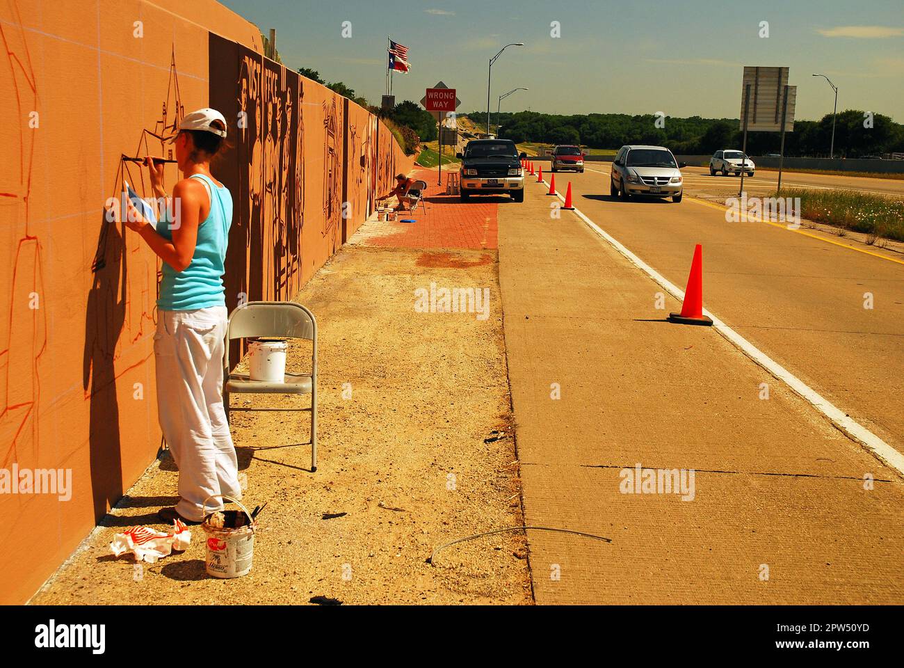 Une jeune femme peint une murale le long d'une autoroute Interstate près de Denton, Texas Banque D'Images