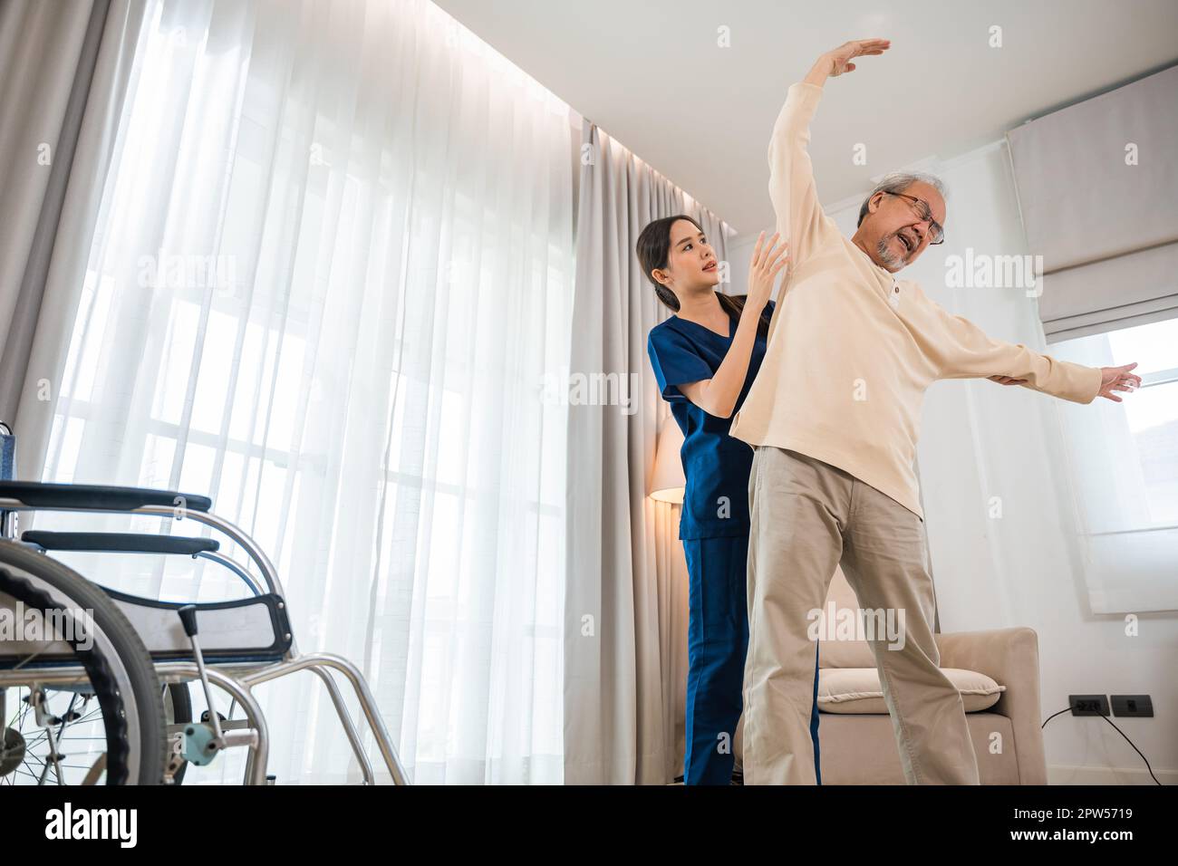 L'homme âgé aime s'entraîner avec un physiothérapeute pour les bras étirés à la maison, un thérapeute asiatique soins infirmiers aux patients aidant les personnes âgées à s'exercer Banque D'Images