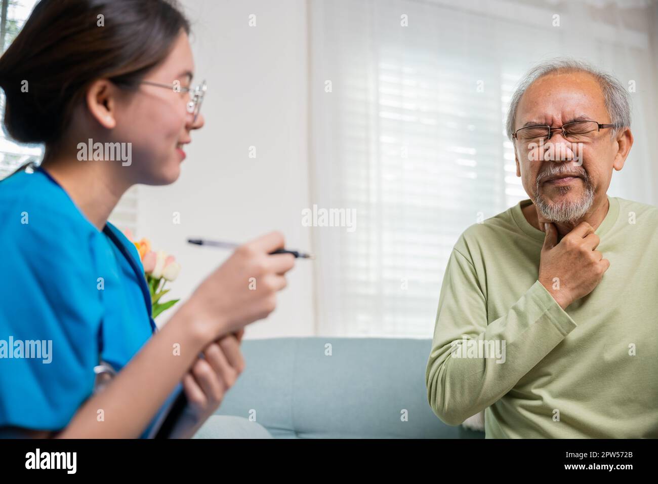 Le médecin-femme examine les ganglions lymphatiques sur le cou âgé pour déterminer si gonflé, mal de gorge, jeune infirmière asiatique vérifiant la douleur de cou de l'homme âgé senior dans la clinique Banque D'Images