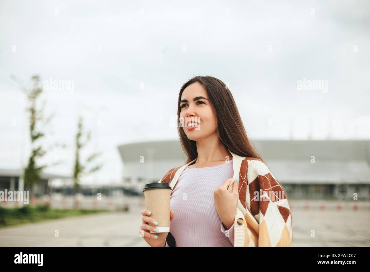 Photo rognée de la jeune femme heureuse avec un café pour aller à la coupe debout à l'extérieur, heureuse femme portant un pull chaud tenant une boisson chaude et appréciant Nice Banque D'Images