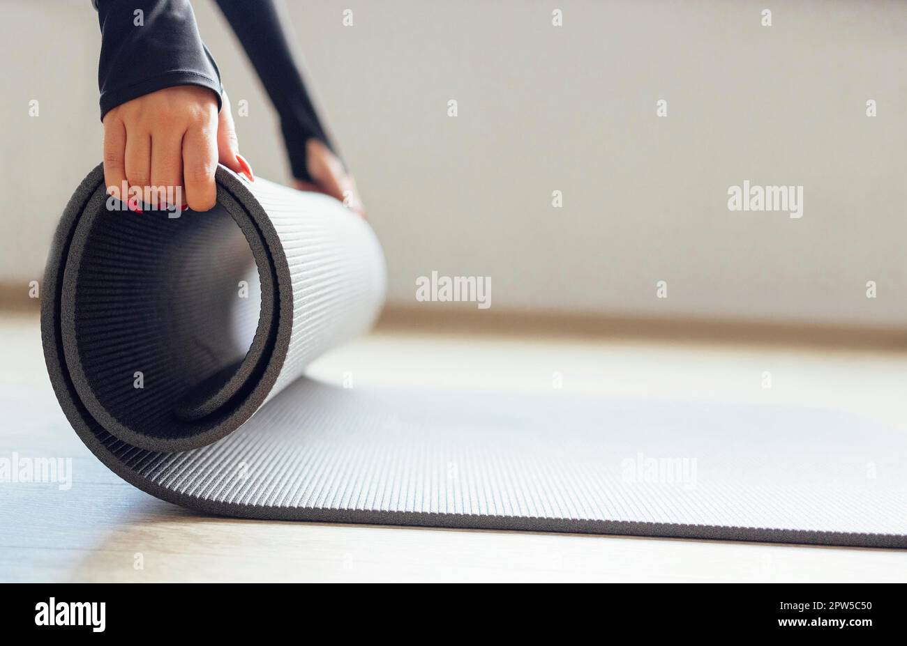 Vue latérale du tapis de roulement féminin fin et anonyme Crop pour pratiquer le yoga dans un studio blanc Banque D'Images