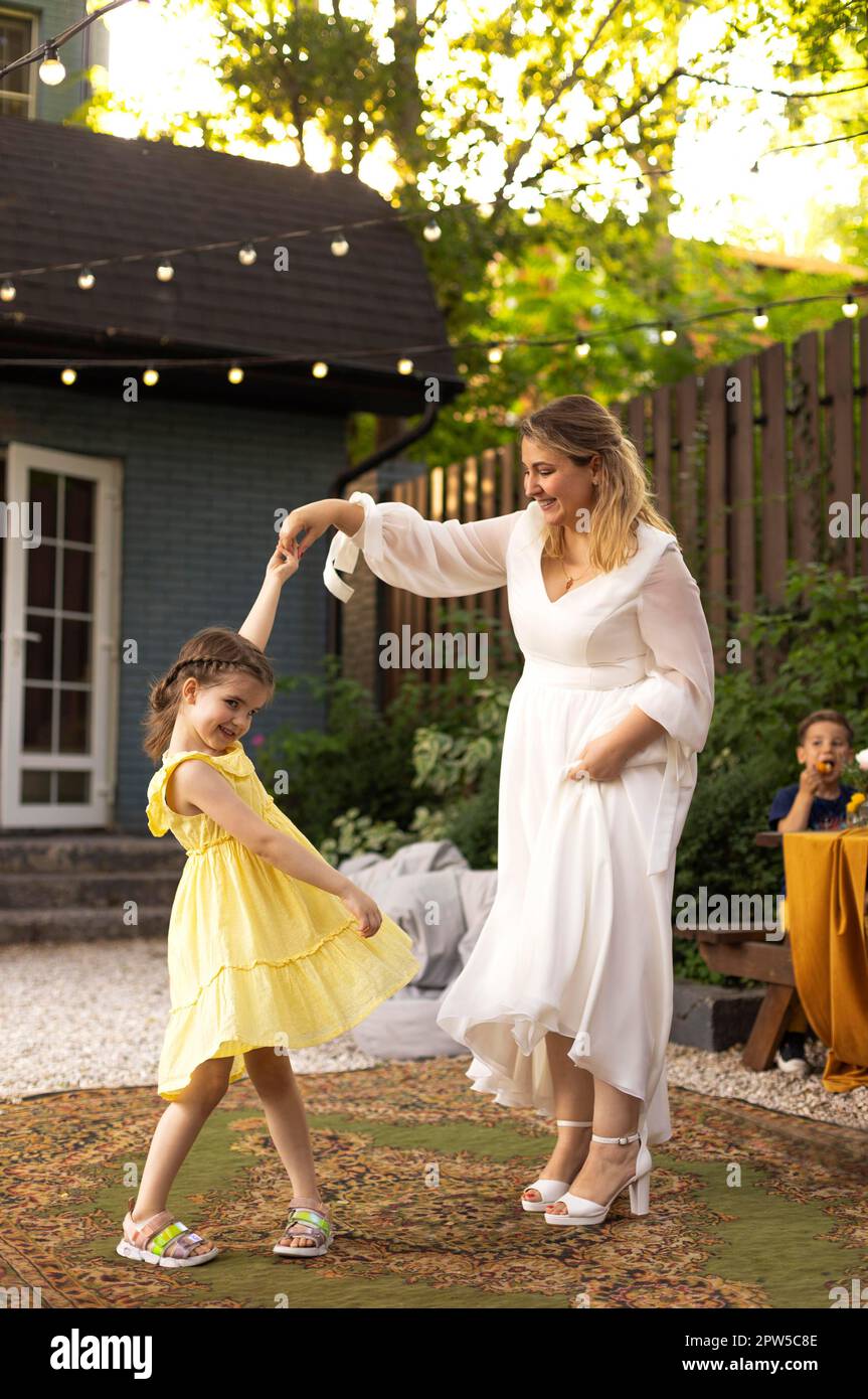 Mère et petite fille s'amusent à l'extérieur. Mariage, belle mariée avec une petite fille dansant ensemble. Amour, famille, célébration Banque D'Images