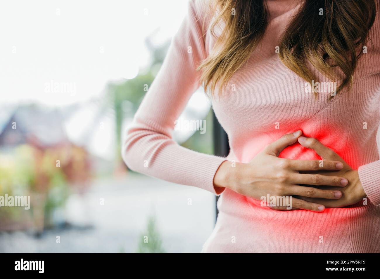 Malade femme malheureux avoir mal à l'estomac à la maison, asiatique jeune femme souffre de maux d'estomac après avoir mangé la nourriture avariée, douleur abdominale des menstruations c Banque D'Images