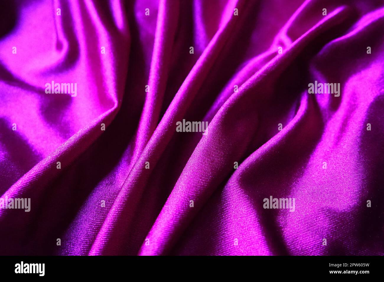 Tissu velours, semblable à la soie. Textiles dans des plis et de belles vagues. Tons violet, rose, magenta sur la drapery. Matériel de couture pour les soirées dres Banque D'Images