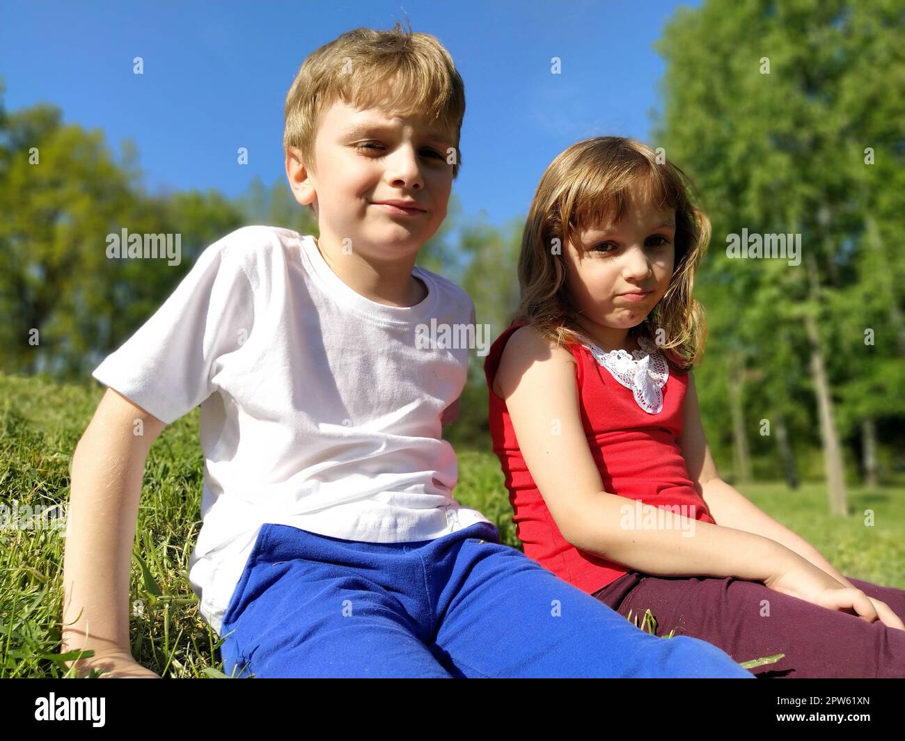 Garçon et fille, frère et sœur. Les enfants dont les visages sont déplaisés regardent la caméra. La fatigue et le caprice sont visibles sur le visage. Été. Un garçon Banque D'Images