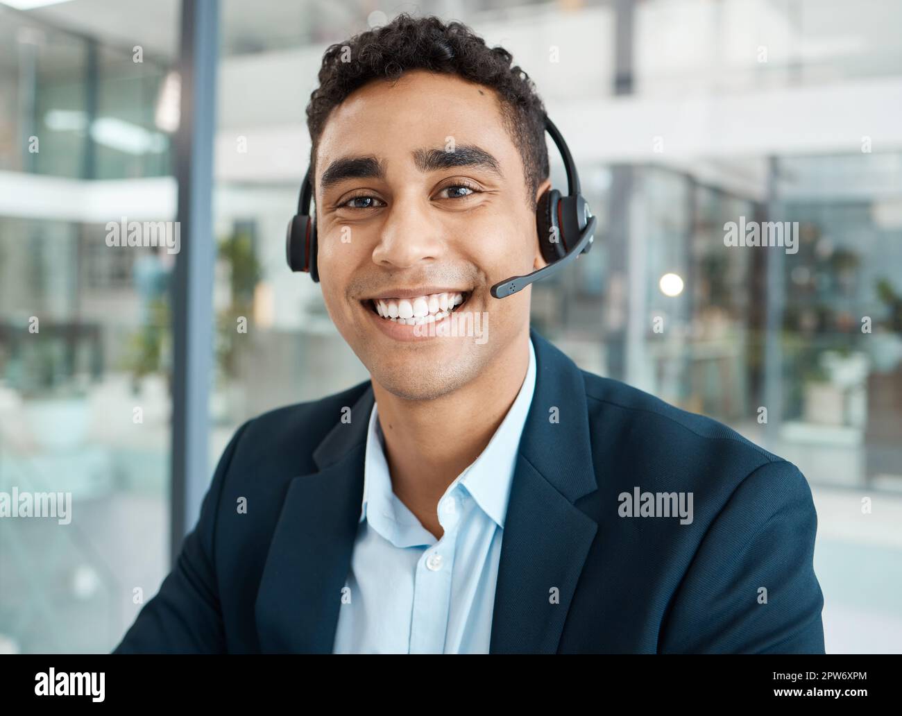Portrait d'un jeune homme de course mixte heureux qui répond aux appels  tout en portant un casque seul au travail. Un secrétaire hispanique  souriant Photo Stock - Alamy