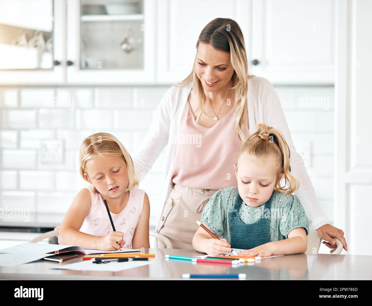 Éducation, apprentissage et devoirs avec une fille, sa sœur et leur mère dans la cuisine à la maison. Mère célibataire aidant, aidant et enseignant son daugh Banque D'Images
