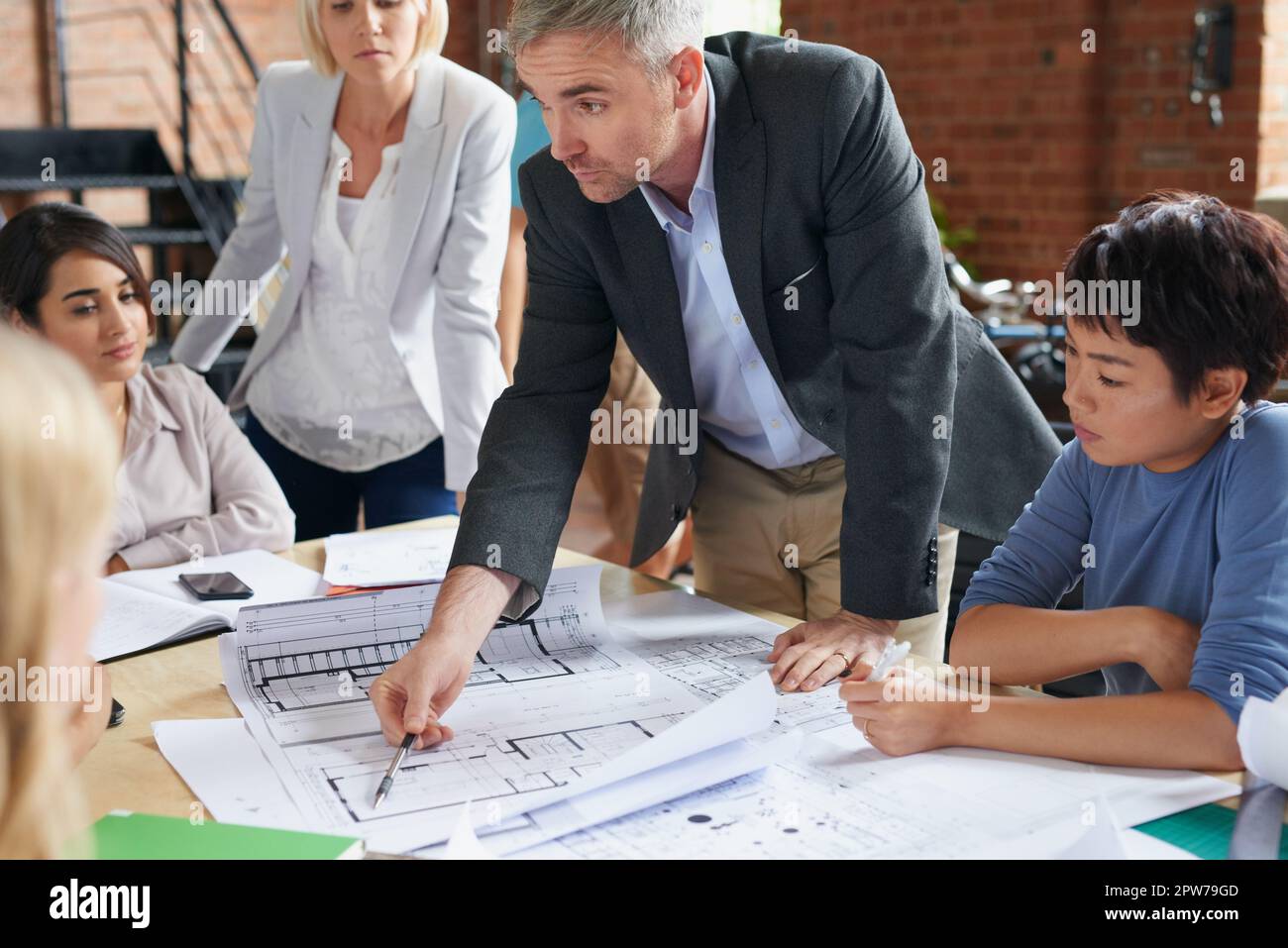 Le client souhaite que nous retravailler cette section. un groupe d'architectes travaillant avec des plans dans un bureau Banque D'Images