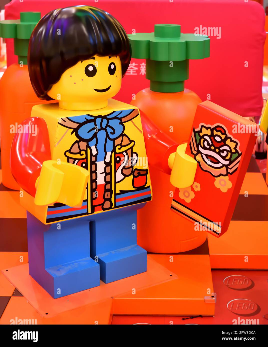 Garçon tenant un paquet rouge, bloc Lego, intérieur Banque D'Images