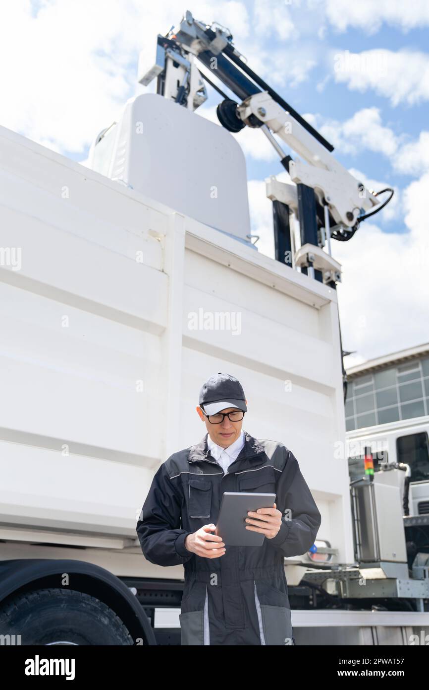 Manager avec une tablette numérique à côté d'un camion à ordures. Photo de haute qualité Banque D'Images