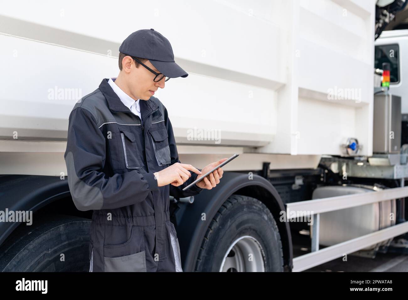 Manager avec une tablette numérique à côté d'un camion à ordures. Photo de haute qualité Banque D'Images