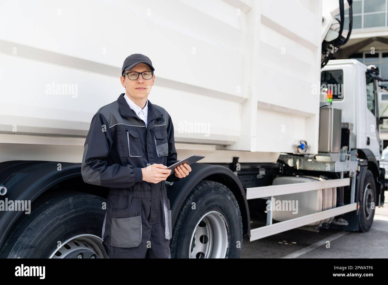 Manager avec une tablette numérique à côté d'un camion à ordures. Photo de haute qualité Banque D'Images