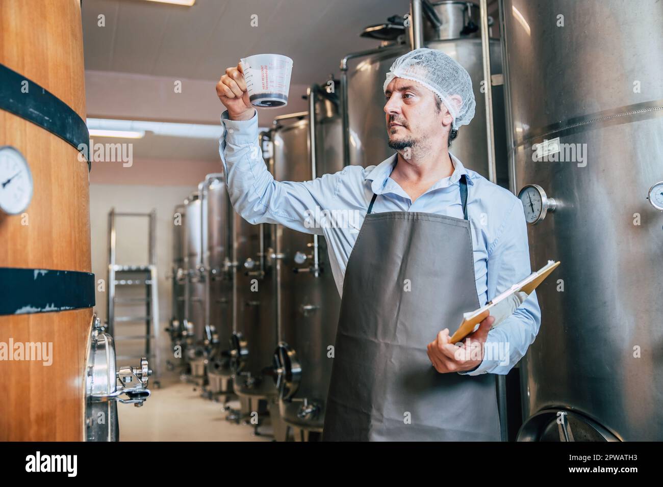 Viticulteur travaillant dans une grande usine moderne de vins alcool industrie de boisson qualité et contrôle de fermentation Banque D'Images