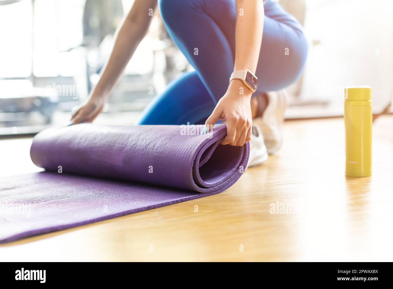 Tapis de yoga. Gros plan les mains des femmes roulent le tapis de yoga d'exercice en caoutchouc TPE sur le sol du club de sport. Banque D'Images