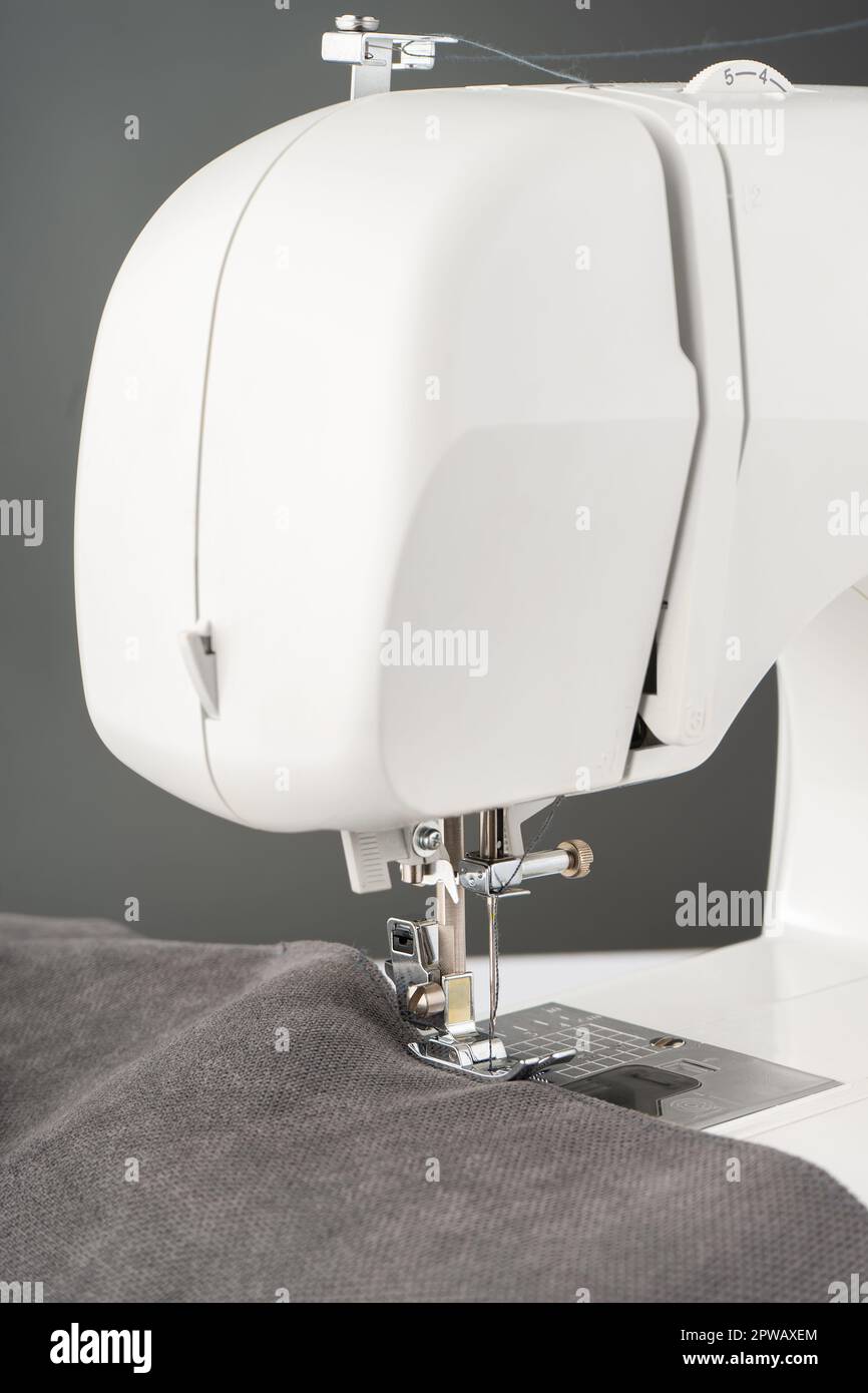Machine à coudre moderne avec tissu gris et. Processus de couture vêtements, rideaux, tissus d'ameublement. Affaires, passe-temps, fait main, zéro déchet, recyclage, réparer le con Banque D'Images