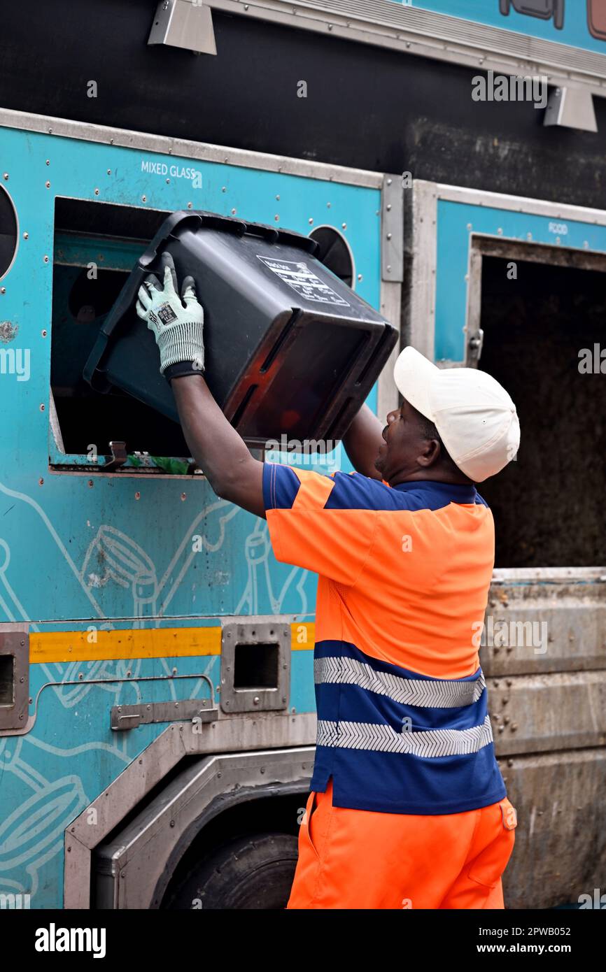 Un ouvrier du conseil vidant la boîte de recyclage des déchets triés par ménage dans un camion de recyclage Banque D'Images