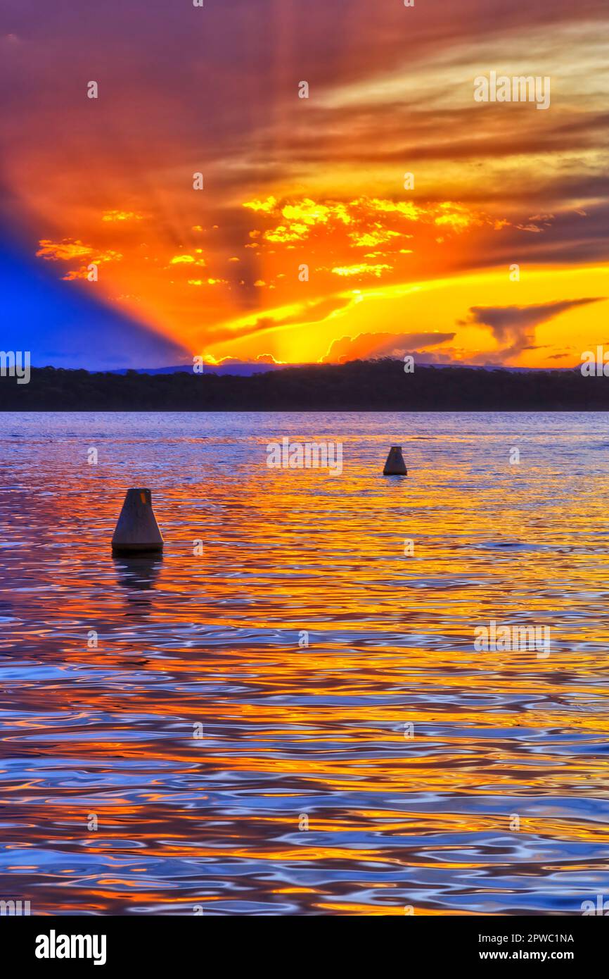 Bouées flottantes sur le lac Macquarie au coucher du soleil depuis la plage de Murraies - paysage australien. Banque D'Images